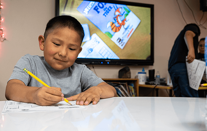 Young male student writing on a desk in class